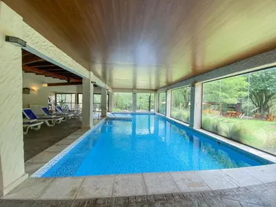 an indoor swimming pool in a house with windows at Posada Alma del Arroyo & Spa in Villa General Belgrano