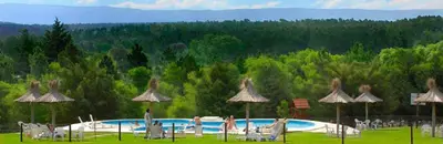 a swimming pool with umbrellas and people standing around it at Cabañas Juan Salvador in Los Reartes