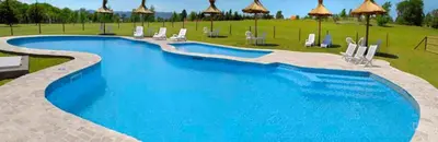 a large blue swimming pool with chairs and umbrellas at Cabañas Juan Salvador in Los Reartes
