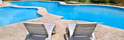 two chairs sitting next to a swimming pool at Cabañas Juan Salvador in Los Reartes