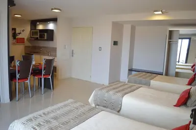 a hotel room with two beds and a table with chairs at Sol de Piedra Apart, Suites & Spa in Cordoba