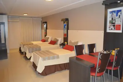 a hotel room with two beds and a table and chairs at Sol de Piedra Apart, Suites & Spa in Cordoba