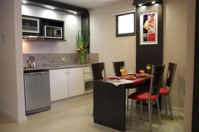 a kitchen with a table and chairs with wine glasses at Sol de Piedra Apart, Suites & Spa in Cordoba