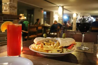 a sandwich and french fries on a table with a glass of wine at Gran Hotel Las Lajas in Villa Carlos Paz