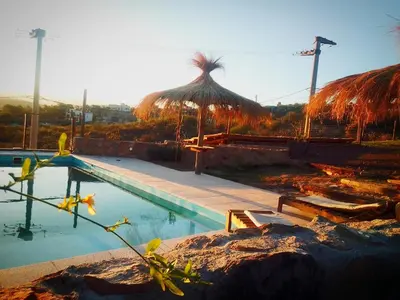 a swimming pool with a straw umbrella and a swimming pool at ALTOS DEL MOLLE en VCP predio con solo 2 cabañas in Villa Carlos Paz