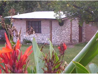 a small stone building with a stone wall and flowers at Cabanas Las Achiras in San Javier