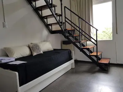 a room with a bed and a spiral staircase at Departamento Loft VCP in Villa Carlos Paz