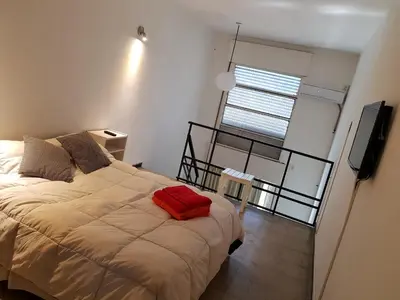 a bedroom with a bed with a red pillow on it at Departamento Loft VCP in Villa Carlos Paz
