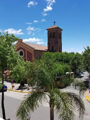 a church with a palm tree in front of a building at Departamento Loft VCP in Villa Carlos Paz
