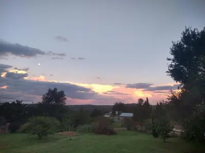 a sunset over a field with trees and a house at Hermosa casa en Potrero de Garay in Potrero de Garay