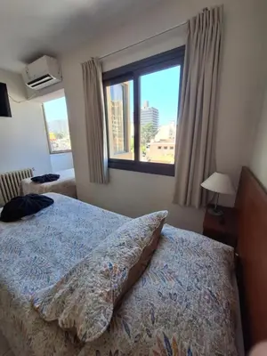 a bedroom with a bed and a large window at Hotel Hurlingham in Villa Carlos Paz