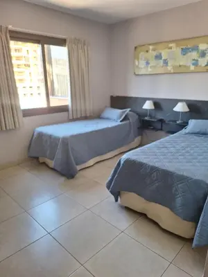 a bedroom with two beds and a window at Hotel Hurlingham in Villa Carlos Paz