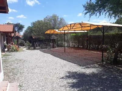 a large orange umbrella on a gravel driveway at Complejo Sagrado Corazón in Merlo