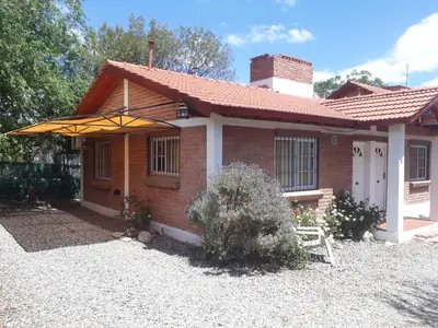 a small brick house with an umbrella in front of it at Complejo Sagrado Corazón in Merlo