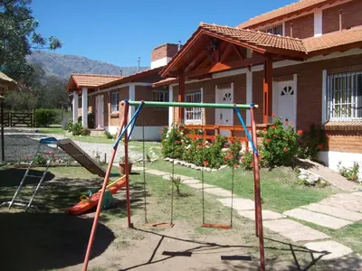 a yard with a swing set in front of a house at Complejo Sagrado Corazón in Merlo