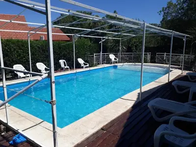 a swimming pool with chairs and a canopy at Complejo Sagrado Corazón in Merlo