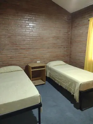 a room with two beds and a table in it at casa villa suiza in Villa Carlos Paz