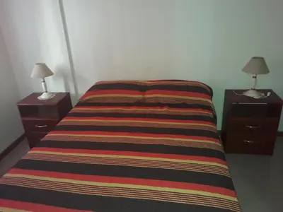 a bed with two night stands and a striped blanket on it at Dpto centrico in Villa Carlos Paz