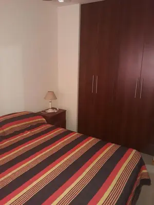 a bedroom with a bed and wooden cabinets at Dpto centrico in Villa Carlos Paz