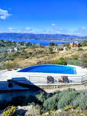 a large swimming pool on a hill next to a body of water at casa del lago -villa carlos paz in Villa Carlos Paz
