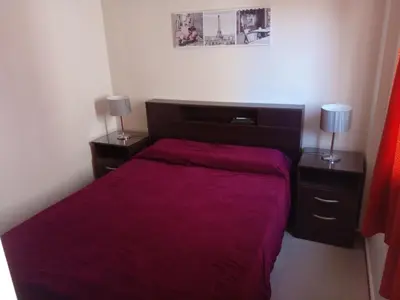 a bedroom with a red bed with two night stands at Departamento en Carlos Paz para familias in Villa Carlos Paz