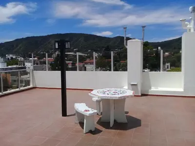 a patio with a table and two benches on a roof at Departamento en Carlos Paz para familias in Villa Carlos Paz