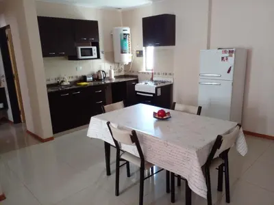 a kitchen with a table with chairs and a white refrigerator at Departamento en Carlos Paz para familias in Villa Carlos Paz