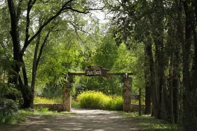 a gate to a garden with a sign on it at Cabañas Am Bach in Villa General Belgrano