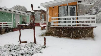 a house covered in snow with a sign in front of it at CABAÑAS LA GUADALUPE in Villa Yacanto