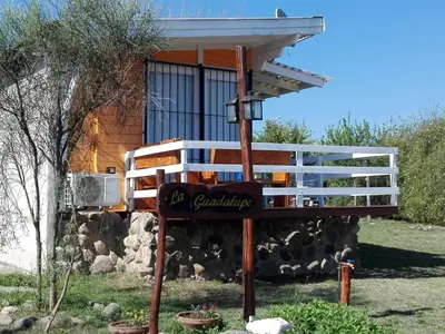a sign in front of a house with a building at CABAÑAS LA GUADALUPE in Villa Yacanto