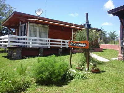 a sign in the grass in front of a house at CABAÑAS LA GUADALUPE in Villa Yacanto