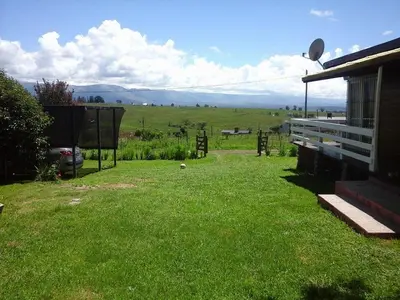 a yard with a house and a field of grass at CABAÑAS LA GUADALUPE in Villa Yacanto