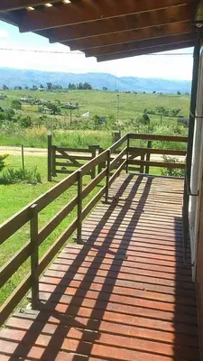 a wooden porch with a fence and a field at CABAÑAS LA GUADALUPE in Villa Yacanto