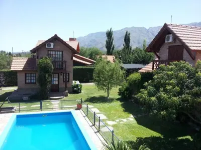 a house with a swimming pool in front of a house at Cabañas Euzkadi in Merlo