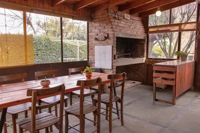 a dining room with a wooden table and a brick fireplace at Cabañas Euzkadi in Merlo