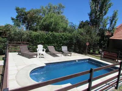 a swimming pool with two chairs and a fence at Chalet Individual Maiten 2 in Merlo