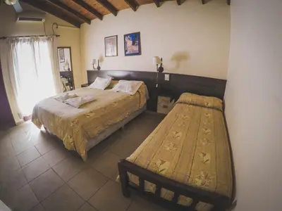 a bedroom with two beds and a bench in it at Cana Blaya Apart Hotel in Merlo