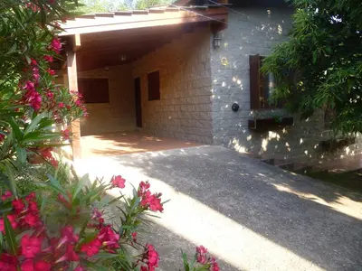 a house with a garage and some pink flowers at Cabanas los lirios in Santa Rosa de Calamuchita