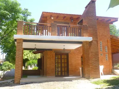 a brick house with a balcony on top of it at Cabanas los lirios in Santa Rosa de Calamuchita