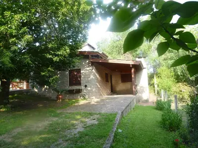 a stone house with a yard in front of it at Cabanas los lirios in Santa Rosa de Calamuchita