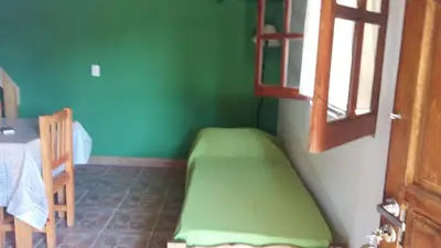 a room with a green wall with a bed in it at Cabañas Kehuen in Villa Amancay