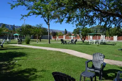 a park with chairs and picnic tables in the grass at Hotel Torres del Sol in Merlo