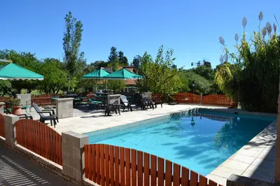 a swimming pool with tables and chairs and umbrellas at Hotel Torres del Sol in Merlo