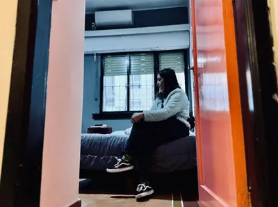 a woman sitting on a couch talking on a cell phone at Lacandona Hostel in Cordoba