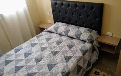 a bedroom with a bed with a quilt on it at Cabañas El Descanso in Villa Carlos Paz