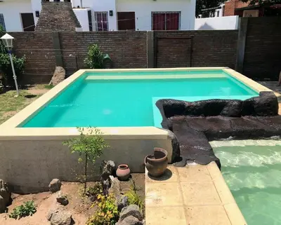 a large swimming pool in a yard with potted plants at Cabañas El Descanso in Villa Carlos Paz