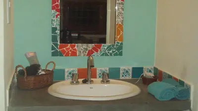 a bathroom sink with a mirror and a basket at Cabaña El Mirador de Bialet Masse in Villa Parque Siquiman