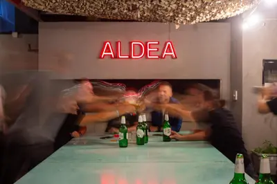 a group of people standing around a table with bottles of alcohol at Aldea Hostel & Café in Cordoba