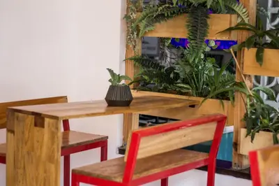 a wooden table with a red chair and some plants at Aldea Hostel & Café in Cordoba