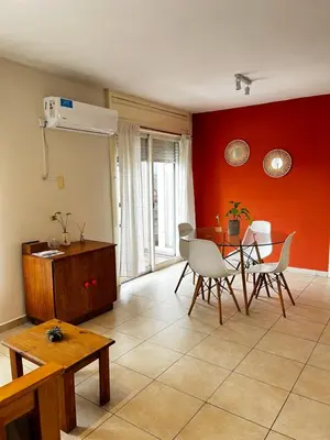 a living room with a table and chairs and red wall at El Abrojal - Departamento con Estacionamiento , zona Patio Olmos in Cordoba